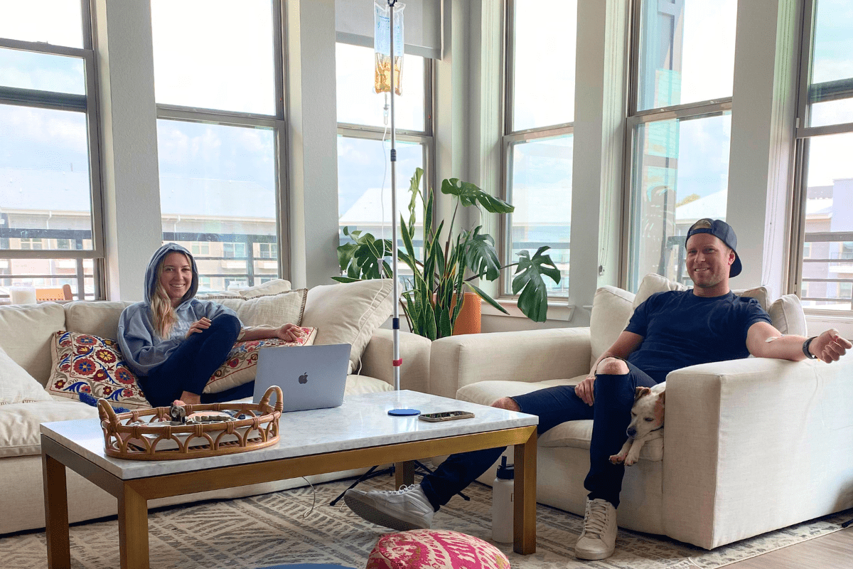 Two people sitting on a couch in front of a laptop.