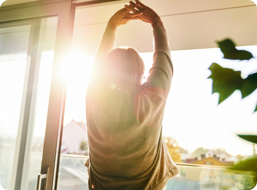 A person stretching in front of the sun.