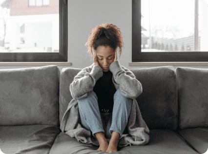 A woman sitting on top of the couch in her pajamas.