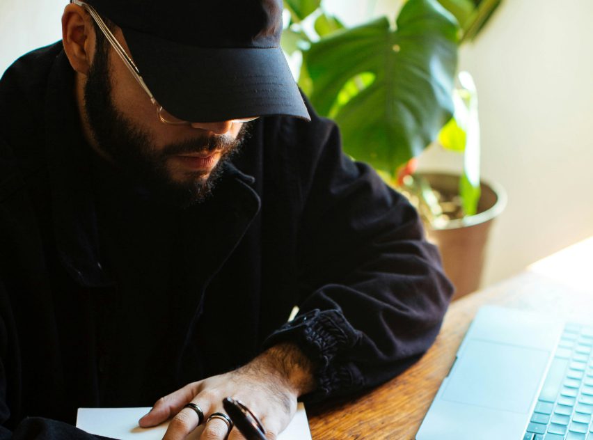 A man writing on paper with a pen.