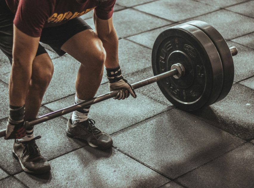 A man is lifting a barbell on the floor