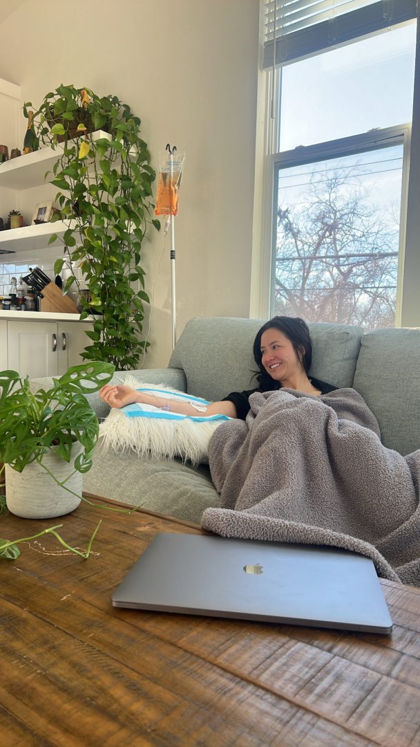 IV Bird client resting on her couch under a blanket during a mobile Super Immunity IV in Austin