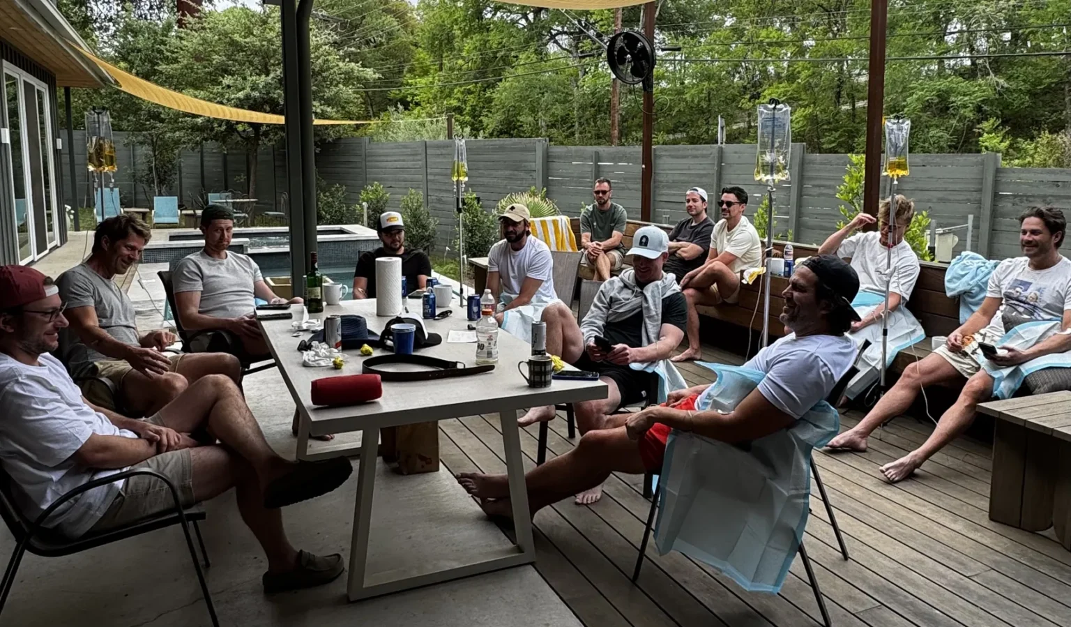 Bachelor group relaxing with mobile IVs around a backyard table at an Austin rental
