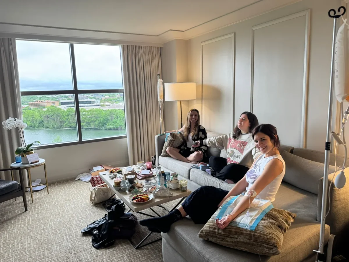 Group of women relaxing with IVs in an Austin hotel suite overlooking the river